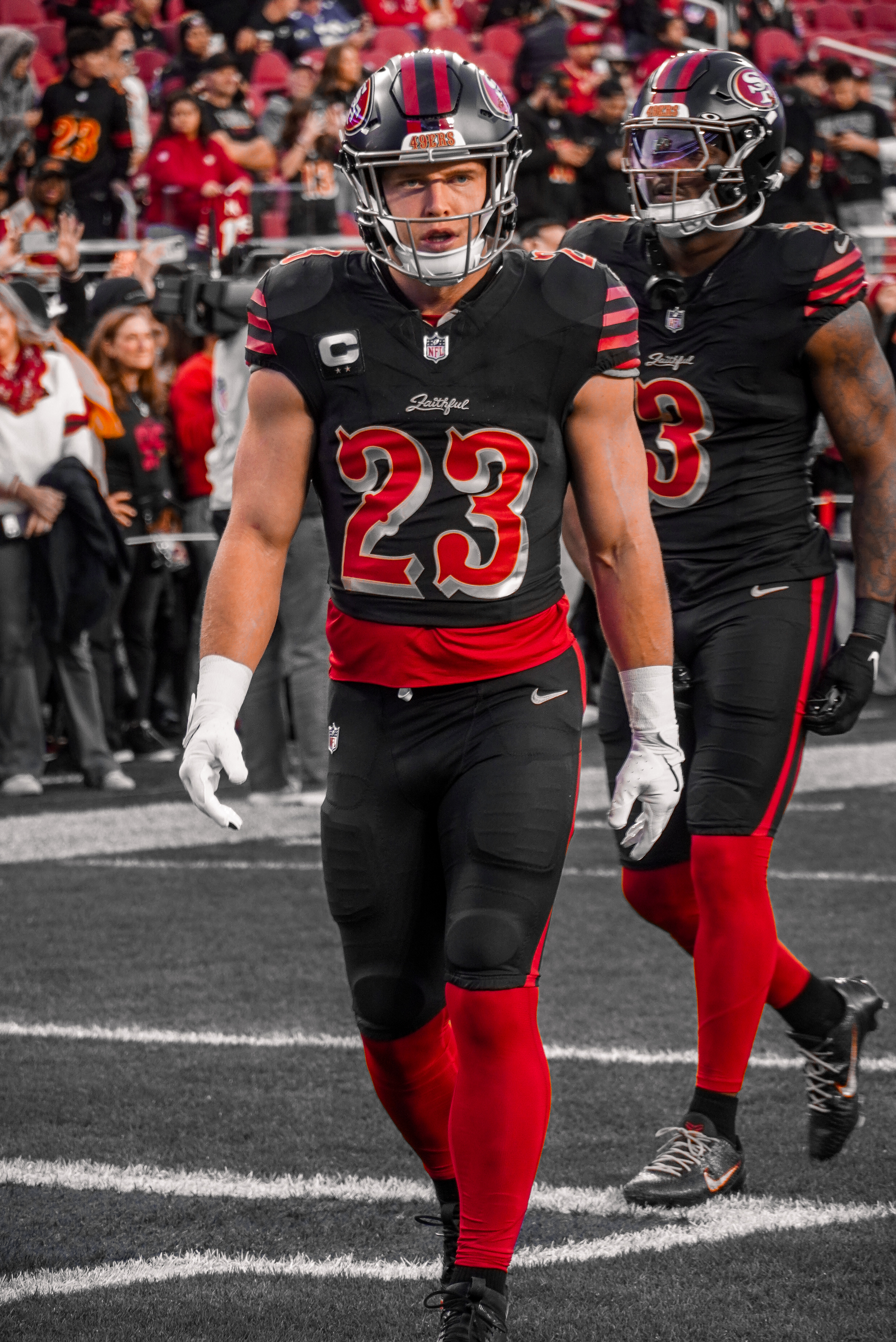 Christian McCaffrey walking onto the field in the 49ers' black alternate uniform